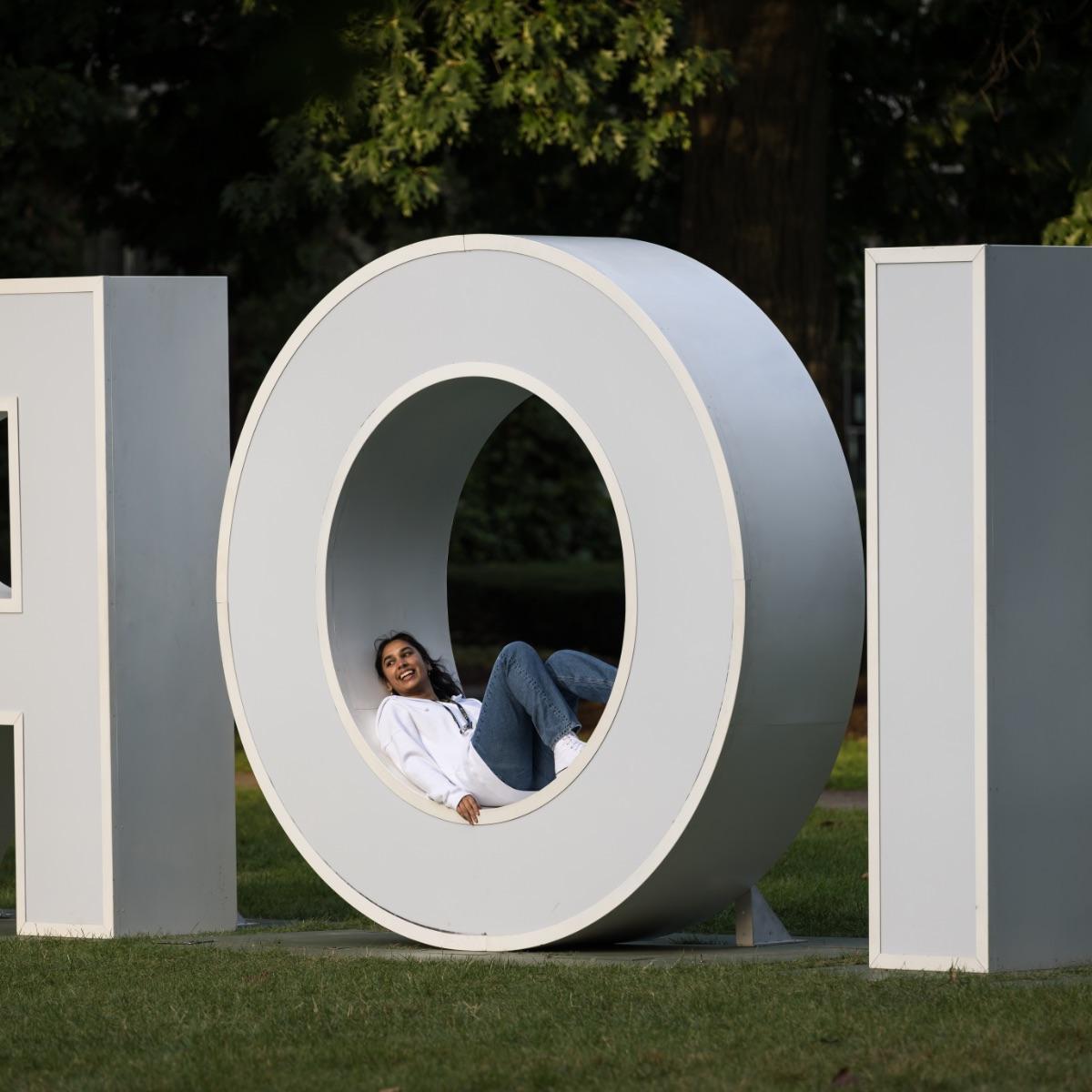 University of Rochester student lays in the O of the large Meliora letters