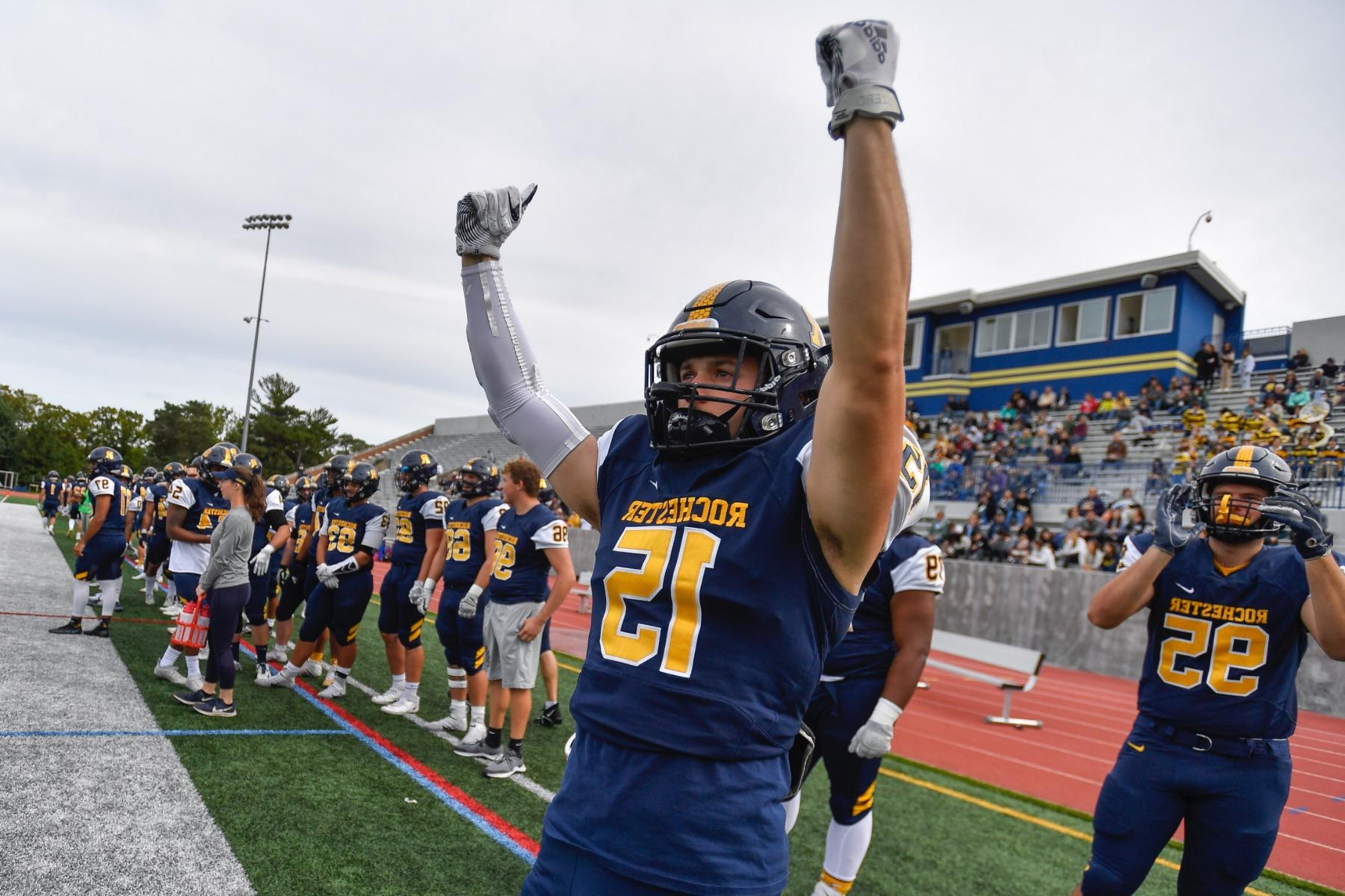 A University of Rochester football athlete raises his arms in victory